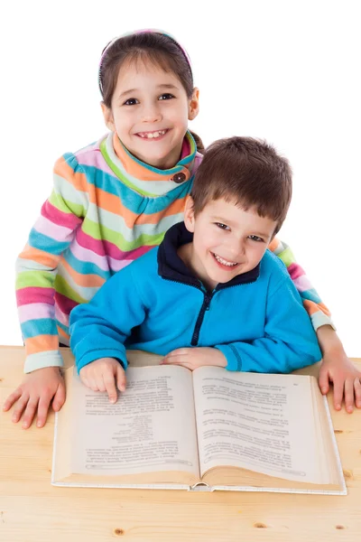 Due bambini felici che leggono il libro a tavola — Foto Stock
