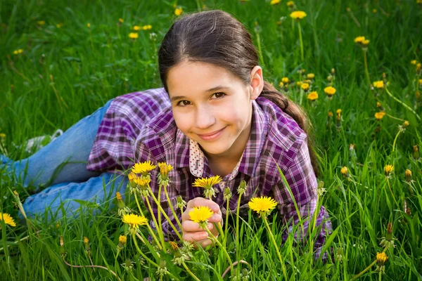 Cute girl on field with dandelions — Stock Photo, Image