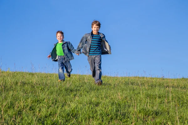 Dois meninos correndo juntos no prado verde — Fotografia de Stock