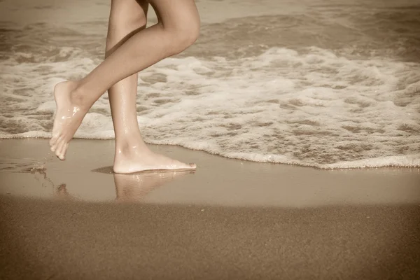 Ung kvinna ben på stranden vid solnedgången — Stockfoto