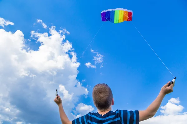 Chłopiec z kolorowy latawiec przeciw błękitne niebo — Zdjęcie stockowe