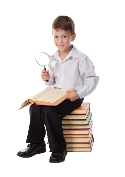 Garoto sorridente sentado em pilha de livros — Fotografia de Stock