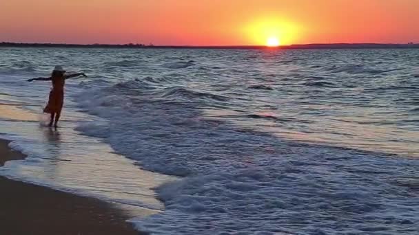 Девушка бежит по пляжу на закате — стоковое видео