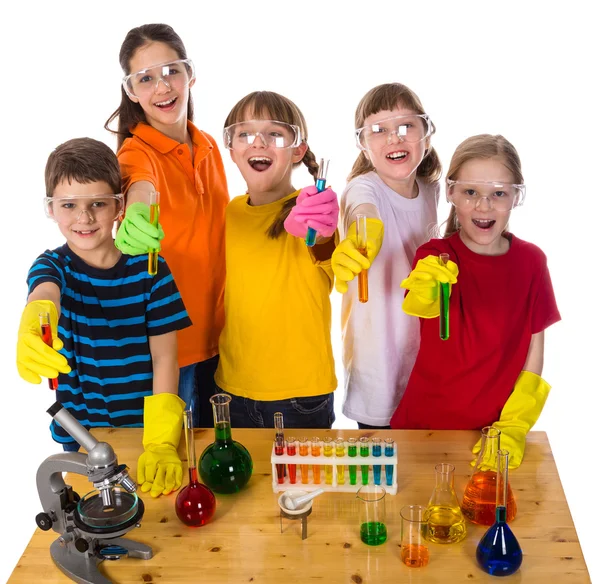 Kids on the table holding chemical test-tubes — Stock Photo, Image