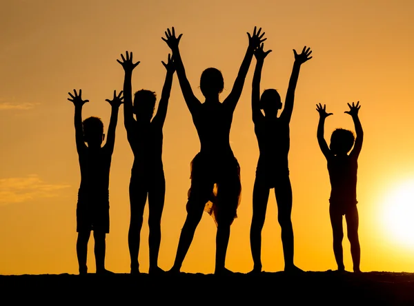 Silueta de los niños contra la puesta del sol — Foto de Stock