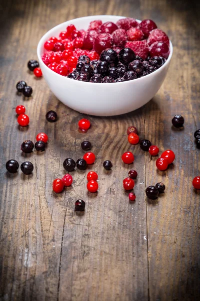 Gefrorene Beeren im Teller auf Holzgrund — Stockfoto