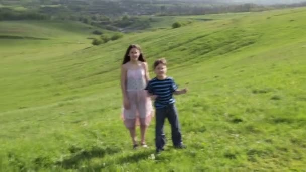 Zwei Kinder fangen die Seifenblasen auf dem Hügel — Stockvideo