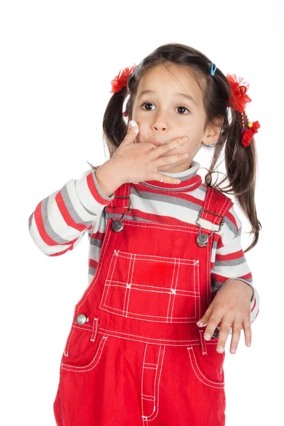 Mädchen leckt ihre Finger, die im Kuchen befleckt sind, isoliert auf weiß — Stockfoto