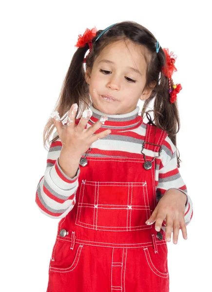 Menina lambe os dedos que estão manchados no bolo, isolado no branco — Fotografia de Stock