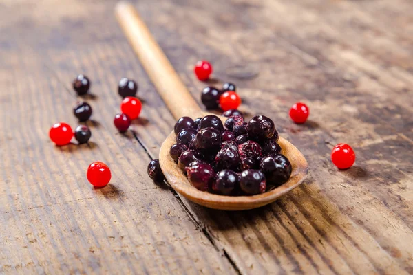 Black currant in wooden spoon on rustic background — Stock Photo, Image