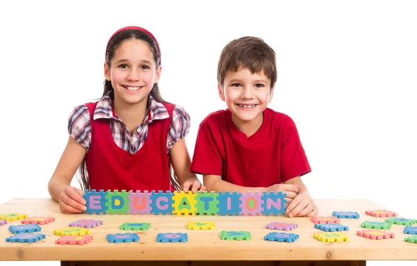 Twee kinderen aan de tafel met puzzel letters — Stockfoto