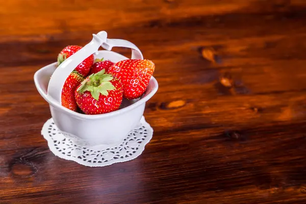 Aardbeien in kom op houten tafel — Stockfoto