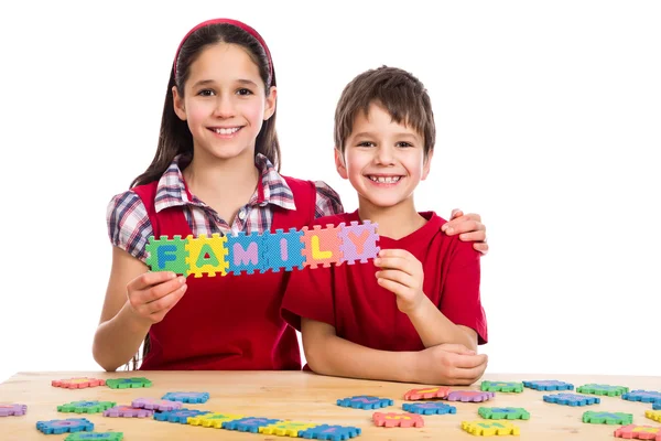 Dos niños en la mesa con letras de rompecabezas — Foto de Stock