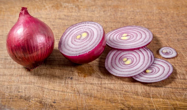 Plátky červené cibule na dřevěné pozadí — Stock fotografie