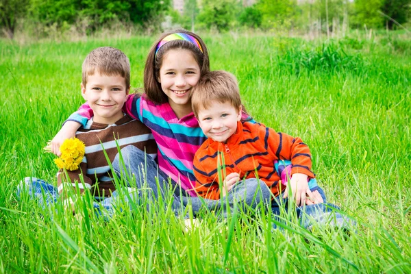 Drie lachende kinderen op groene weide — Stockfoto