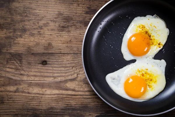 To stegte æg i gryde på bordet - Stock-foto