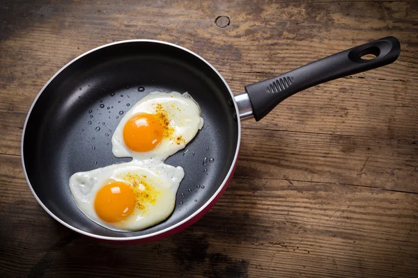 Жарящие яйца в сковороде на столе — стоковое фото