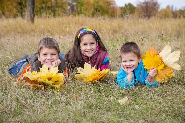 Three kids with autumn leaves — Stock Photo, Image