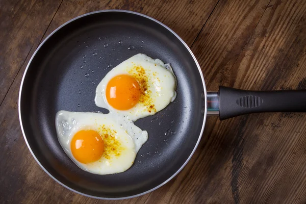 Eier in Pfanne auf Holztisch braten — Stockfoto