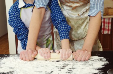 küçük kız annesi pişirmeye yardımcı oluyor