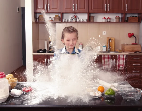 little girl is helping to bake  in a messy  kitchen