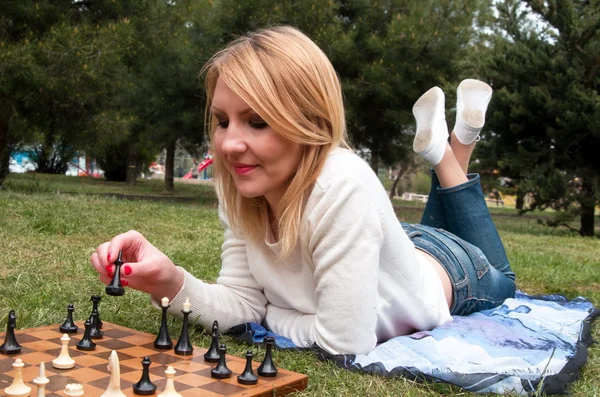 Mulher pondera o próximo movimento no jogo de xadrez, sentada em