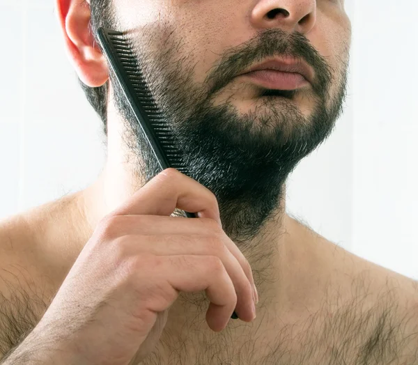 Мужчина расчесывает бороду крупным планом — стоковое фото