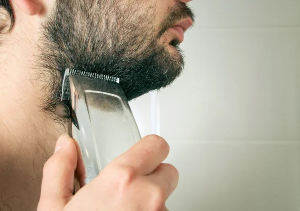 Человек стрижет бороду волосы крупным планом — стоковое фото