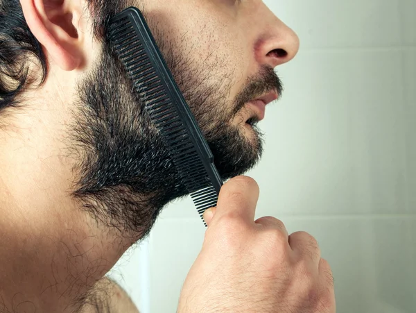 Чоловік розчісує волосся з бородою крупним планом — стокове фото