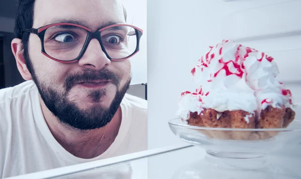 Homem engraçado vê o bolo doce na geladeira — Fotografia de Stock