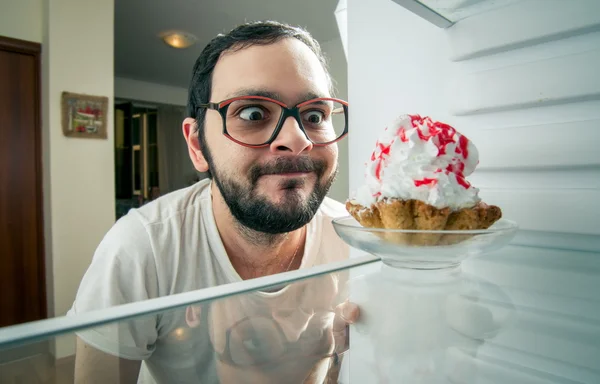 Lustiger Mann sieht den süßen Kuchen im Kühlschrank — Stockfoto