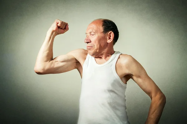 Смешной пожилой человек показывает мышцы — стоковое фото