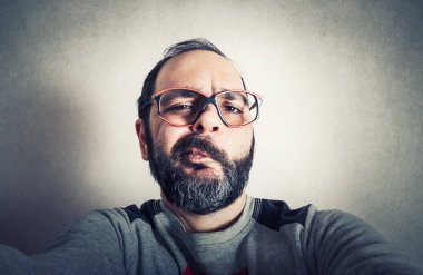 Sakallı komik adam surat ifadeleri yapıyor.