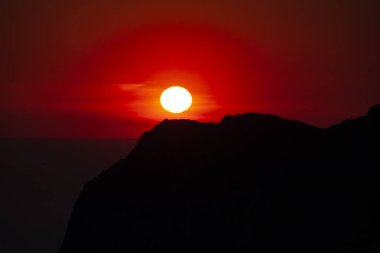 Körfez kıyısının silueti, yukarıdan gökyüzü açık kırmızı günbatımı manzaralı.