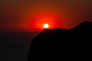 Körfez kıyısının silueti, yukarıdan gökyüzü açık kırmızı günbatımı manzaralı.