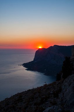 Körfez kıyısının silueti, yukarıdan gökyüzü açık kırmızı günbatımı manzaralı.