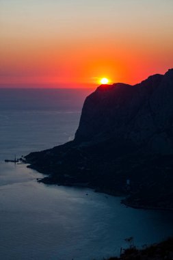 Körfez kıyısının silueti, yukarıdan gökyüzü açık kırmızı günbatımı manzaralı.