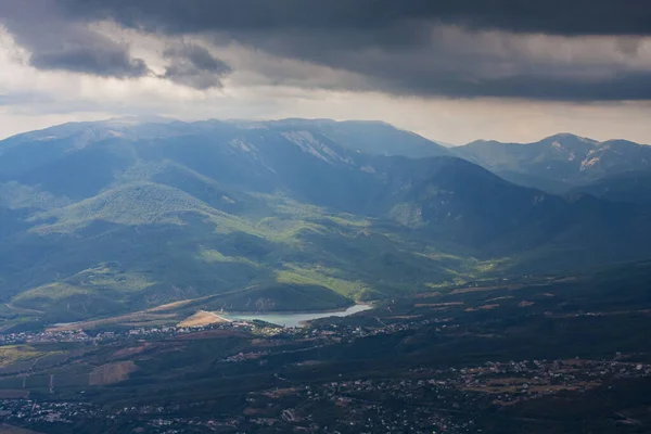 Güneşli bir günde dağlık arka planda yeşil, vahşi bir vadide bulutlu bir manzara