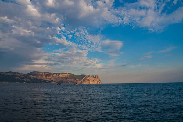 Güneş denizin üzerindeki bulutların arasından aydınlanıyor. Sahil gün batımı