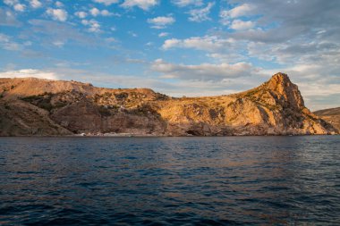 Güneş, denizin üzerindeki bulutların arasından aydınlanıyor.