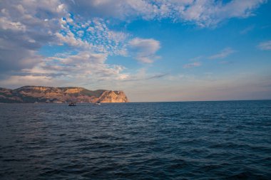 Güneş, denizin üzerindeki bulutların arasından aydınlanıyor.