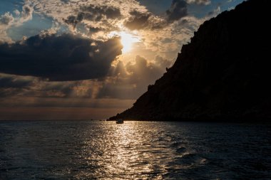 Güneş, denizin üzerindeki bulutların arasından aydınlanıyor.