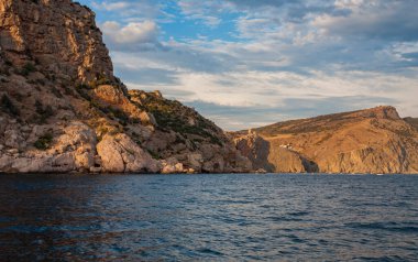 Güneş, denizin üzerindeki bulutların arasından aydınlanıyor.