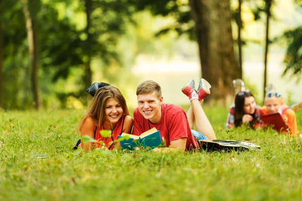 Coppia studenti di successo con un libro di testo in un parco — Foto Stock