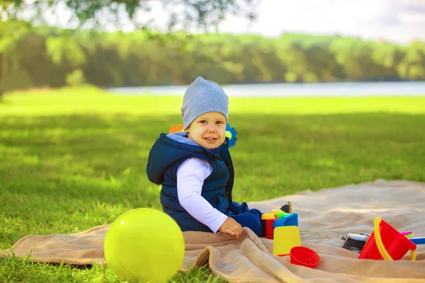 Szczęśliwy chłopczyk z zabawkami na pikniku — Zdjęcie stockowe