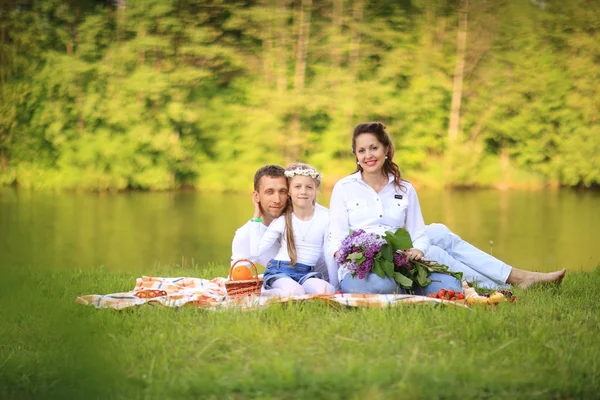 Lycklig far till en dotter och en gravid mamma på en picknick. — Stockfoto