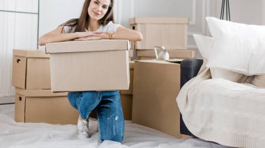 Yeni dairede kutuları açan mutlu genç kadın.