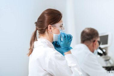 Kapat. Laboratuvar masasında oturan kadın bilim adamı..