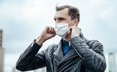 Sokakta duran koruyucu bir maske takan genç adam.