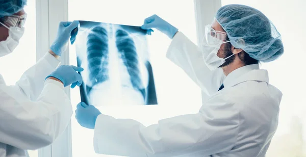 De cerca. médicos con máscaras protectoras que observan una radiografía de los pulmones . — Foto de Stock